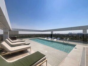 A rooftop pool area with lounge chairs and a clear view of the city skyline. - Minimalist 2 Bedroom l near Cricket Stadium (Dubai Sports City)