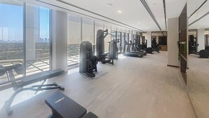 Ett modernt gym med olika typer av träningsutrustning, stora fönster och utsikt över staden.