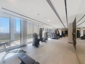 Ein modernes Fitnessstudio mit verschiedenen Trainingsgeräten, großen Fenstern und Blick auf die Stadt.