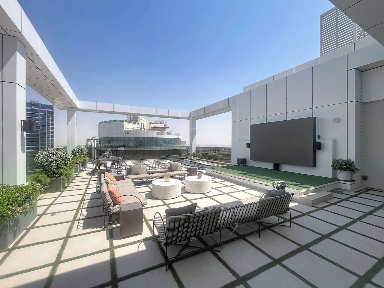 A rooftop terrace with outdoor seating, a flat-screen TV, and a view of the cityscape.