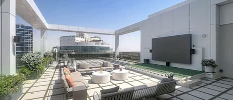 A rooftop terrace with outdoor seating, a flat-screen TV, and a view of the cityscape.