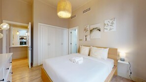 Quarto de hotel com cama, mesa de cabeceira e vista para a cozinha.