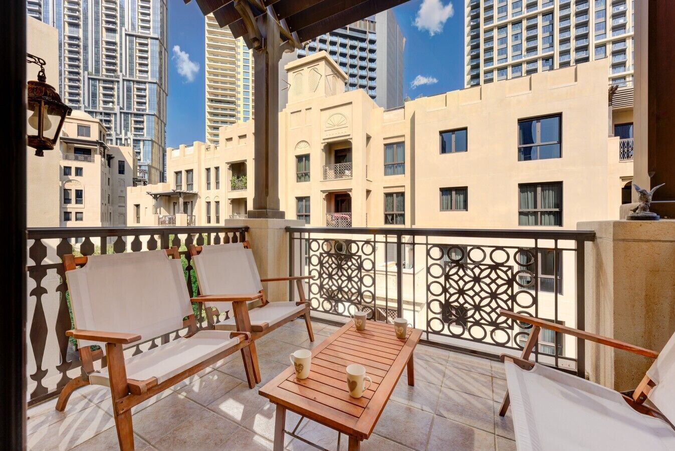 A balcony with wooden furniture, a table, and a decorative railing.