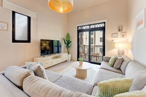 A modern living room with a sofa set, a flat-screen TV, a coffee table, and a balcony with outdoor furniture. - Central 1 Bed l Minutes Walk to Dubai Mall (Downtown)