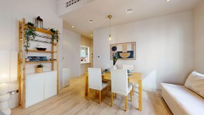 Ein modernes Wohnzimmer mit Essbereich, heller Möbel und Holzboden.