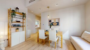 A modern living room with a dining area, white furniture, and a wooden floor. - Central 1 Bed l Minutes Walk to Dubai Mall (Downtown)