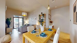 A modern dining area with a wooden table set for four, a gray sofa in the background, and a balcony with a view. - Central 1 Bed l Minutes Walk to Dubai Mall (Downtown)