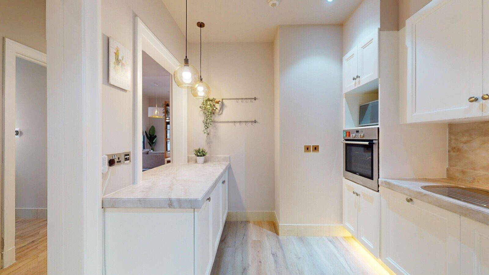 A modern kitchen with white cabinetry, a marble countertop, and a built-in oven.
