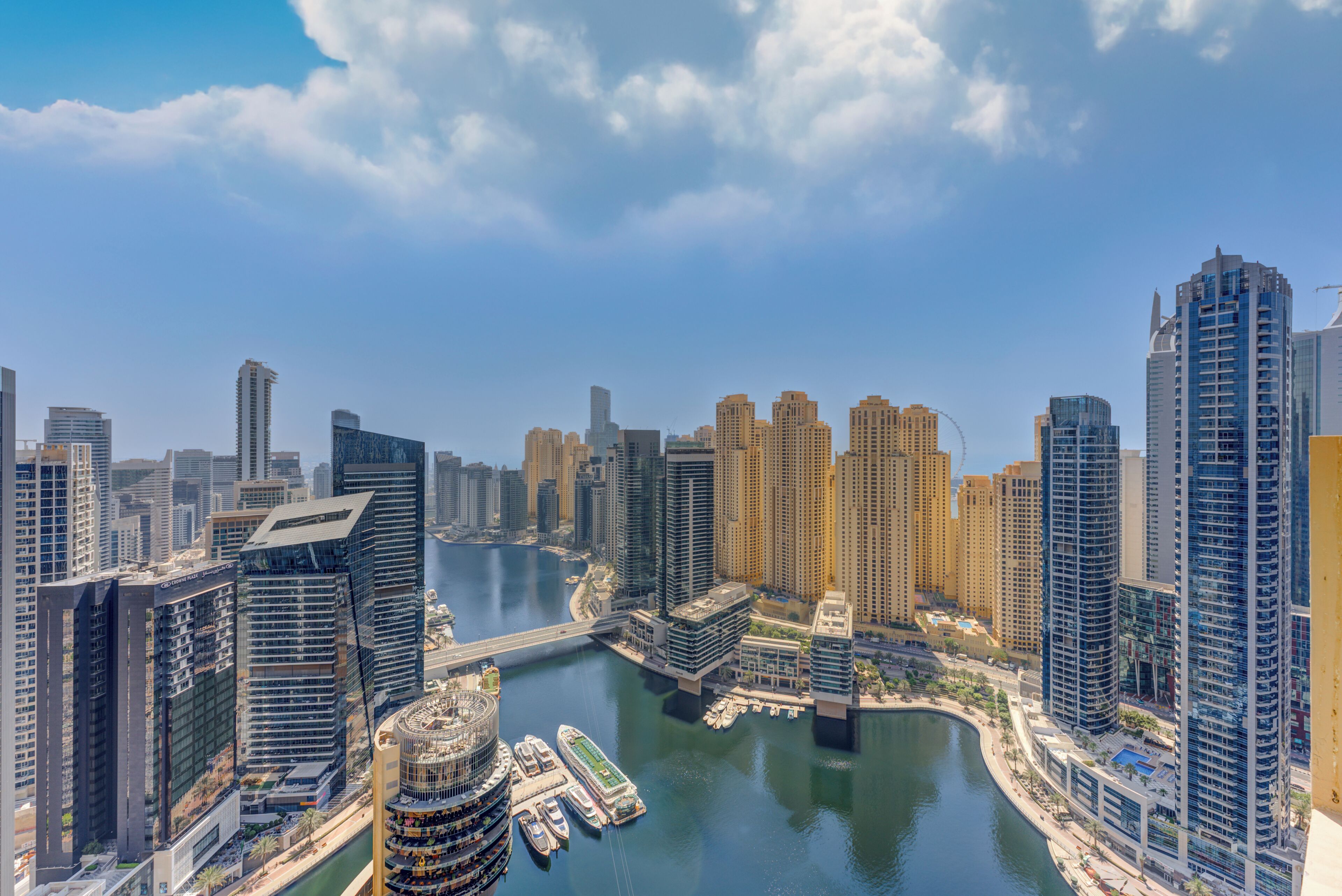 A cityscape with modern high-rise buildings, a marina with boats, and a river.