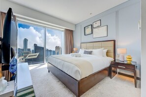 A hotel room with a large bed, a desk with a computer, a TV, and a city view. - Overlooking 1 Bed l Skyline Views l Mall Access (Dubai Marina)