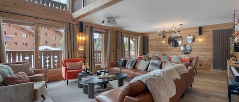 A spacious living room with a large sofa, a coffee table, and a dining area with a piano.