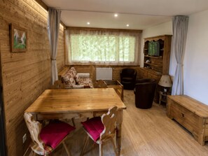 A cozy cabin interior with a wooden dining table, chairs, a sofa, a television, and a cabinet. - Central apartment, pets allowed - 5 guests (Châtel)