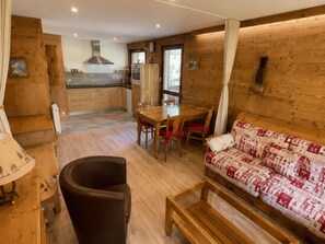 A wooden interior with a dining table, chairs, a sofa, and a kitchen area. - Central apartment, pets allowed - 5 guests (Châtel)
