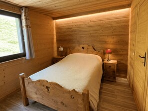 A wooden room with a bed, a nightstand, and a window with curtains. - Central apartment, pets allowed - 5 guests (Châtel)