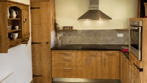 Uma cozinha com armários de madeira, um exaustor de aço inoxidável e um forno embutido.
