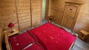 Quarto de madeira com uma cama, um guarda-roupa e uma pequena mesa.