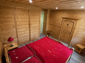 Ein Zimmer mit Holzboden, einem Bett, einem Kleiderschrank und einem kleinen Tisch.