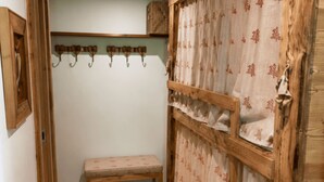 Um quarto com um banco de madeira, um cabide fixado na parede e uma cortina com padrão floral.