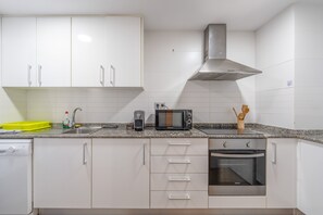 A kitchen with white cabinets, a stainless steel range hood, a microwave, and an oven. - Apartment 'Edimar' with Balcony and Air Conditioning (Benidorm)