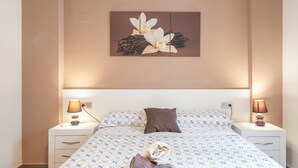 A hotel room with a bed, two bedside tables, a night lamp, a pillow, and a wall-mounted artwork. - Apartment 'Edimar' with Balcony and Air Conditioning (Benidorm)