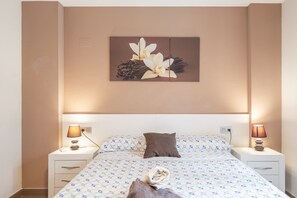 A hotel room with a bed, two bedside tables, a night lamp, a pillow, and a wall-mounted artwork. - Apartment 'Edimar' with Balcony and Air Conditioning (Benidorm)