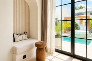 A modern interior with a seating area, a wooden stool, and a view of an outdoor swimming pool. - Private 1BR Pool Villa with Bathtub, BBQ & Sunken Lounge in Bingin (Bingin)