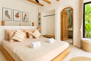 Une chambre à coucher avec un lit, des oreillers, une serviette et des œuvres d’art accrochées au mur.