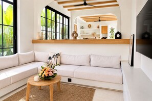 Un salon moderne avec un canapé, une table basse agrémentée de fleurs et un téléviseur.