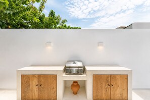 An outdoor kitchen with a built-in grill, wooden cabinets, and a terracotta pot. - Private 1BR Pool Villa with Bathtub, BBQ & Sunken Lounge in Bingin (Bingin)