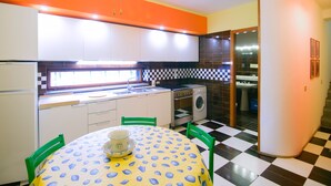 A compact kitchen with a dining area, featuring a checkered floor, a table with a patterned tablecloth, and a refrigerator. - A retreat for relaxation and nature. (Ascea)
