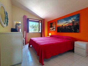 A bedroom with a bed, a nightstand, a lamp, a window with curtains, a painting, and a mirror. - A retreat for relaxation and nature. (Ascea)