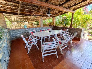 An outdoor patio with a round table and white chairs, surrounded by a brick wall and greenery. - A retreat for relaxation and nature. (Ascea)