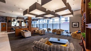 A modern lobby with a reception desk, seating area, and large windows. - Student Only St Andrew Street (Aberdeen)