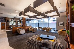 A modern lobby with a reception desk, seating area, and large windows. - Student Only St Andrew Street (Aberdeen)
