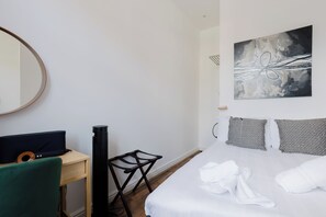 A hotel room with a bed, a desk with a computer, a chair, a standing heater, and a painting on the wall. - Musical 2BDR Retreat in the Heart of Camden (Greater London)