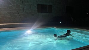 A swimming pool with clear water, surrounded by stone walls.