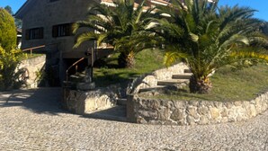 A stone building with a tiled roof, a chimney, and a cobblestone courtyard.