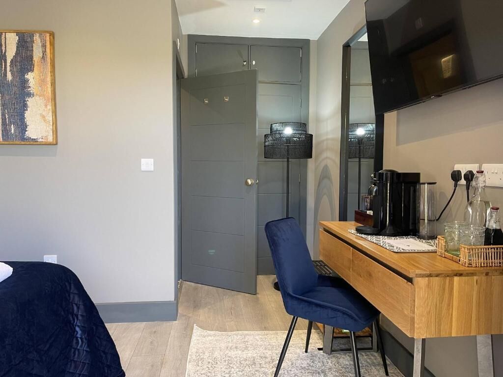 Un dormitorio con cama, un escritorio con silla, una lámpara y un televisor en la pared.