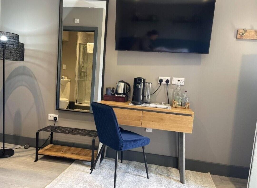 A modern room with a desk, chair, and a flat-screen TV mounted on the wall.