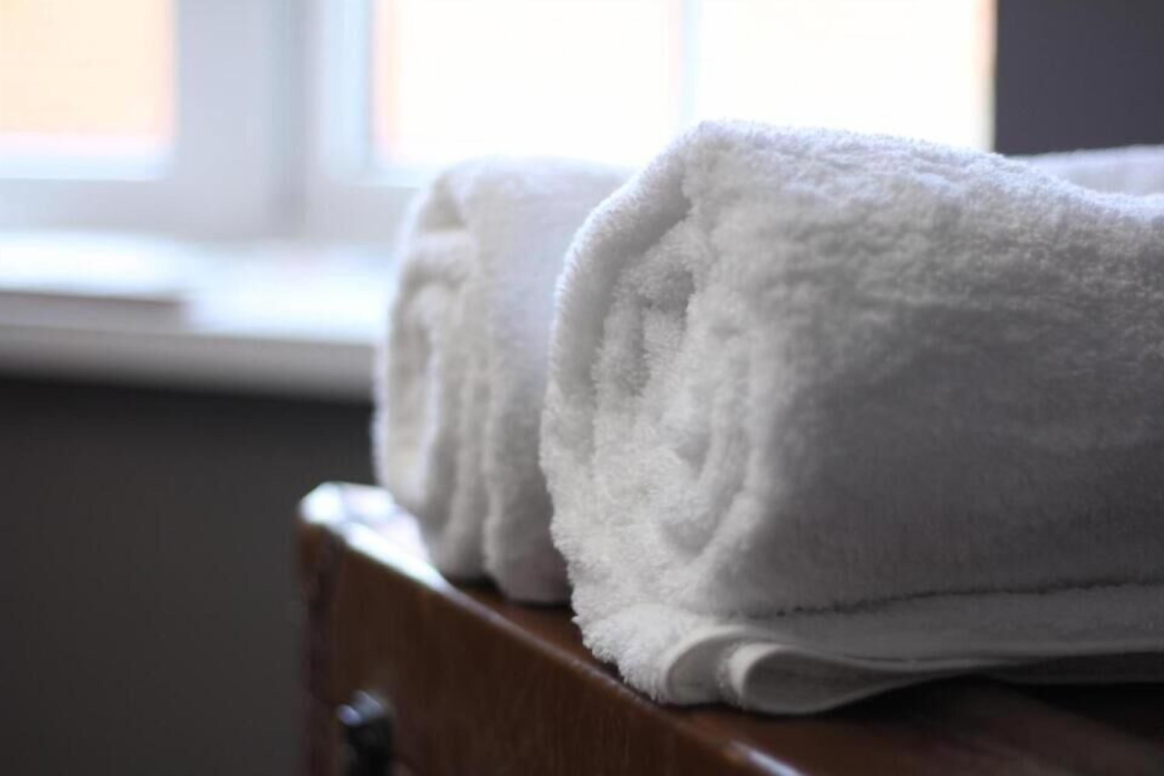 A stack of white towels on a wooden surface.