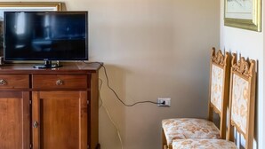 A room with a wooden cabinet, a television, a bench, and a painting on the wall. - Casa Paola - Iglesias (Iglesias)