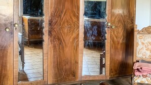 A wooden wardrobe with mirrored doors, a ceiling light fixture, and a tiled floor. - Casa Paola - Iglesias (Iglesias)