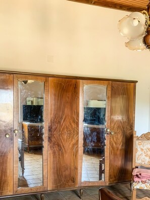 Ein Holzkleiderschrank mit Spiegelüren, eine Deckenleuchte und ein Fliesenboden.