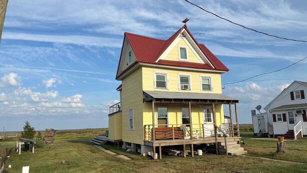 A two-story house with a red roof, a porch, and a small deck. - Water Front 1 bedroom house on tranquil Smith Island (Smith Island)