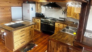 A compact kitchen with wooden cabinets, a stove, and a refrigerator. - Water Front 1 bedroom house on tranquil Smith Island (Smith Island)
