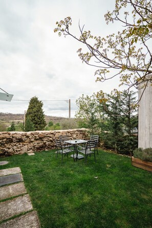 A stone wall, a grassy yard, and a table with chairs.
