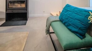 Una sala de estar moderna con chimenea, un sofá verde y un banco de madera.