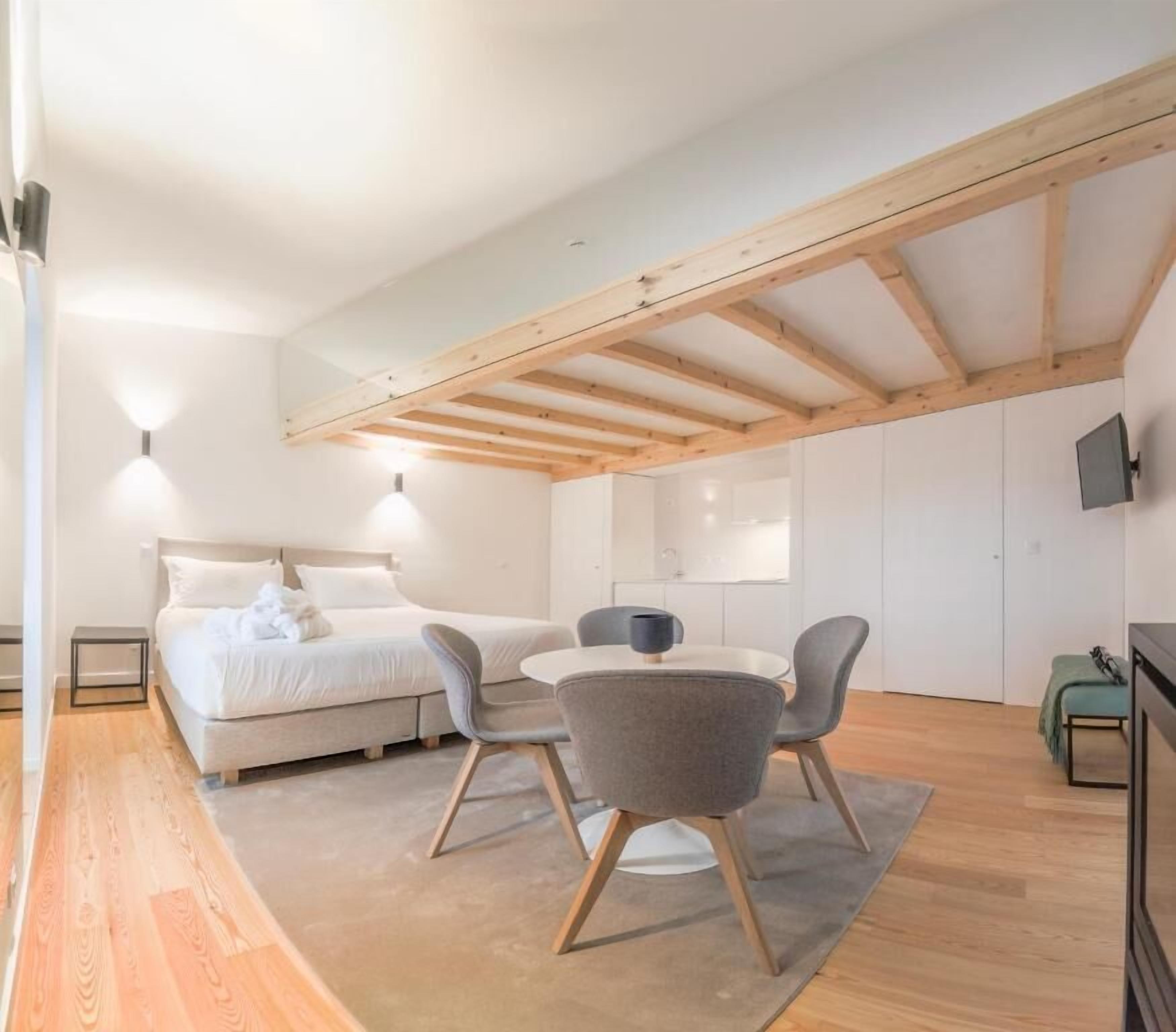 Un dormitorio con cama, mesitas de noche, un escritorio y sillas.