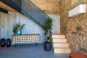 A staircase leading to a stone wall, a wooden bench, and potted plants.