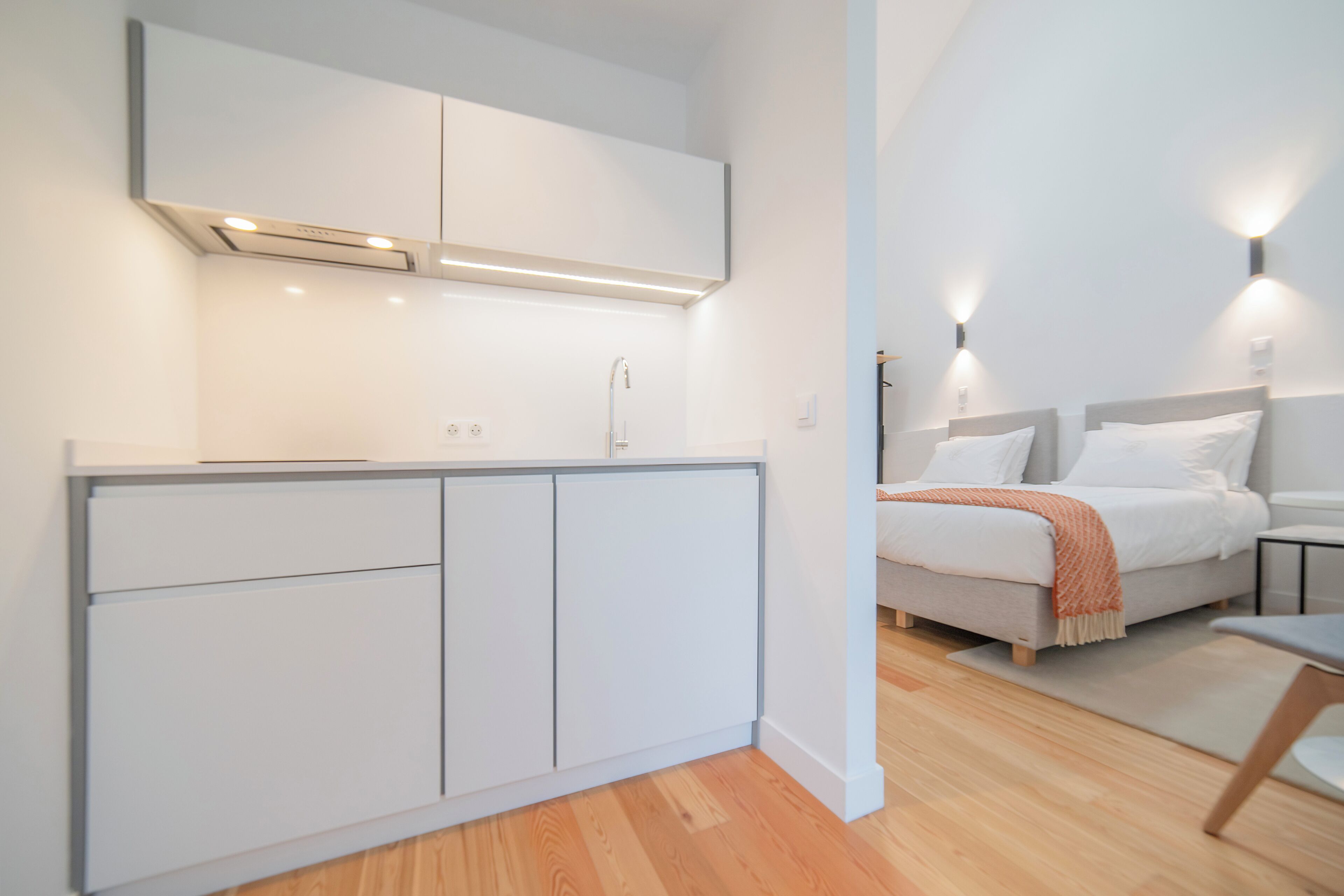 Habitació d'hotel moderna amb armari integrat, un llit amb capçalera, taules de nit i una petita zona de seients.